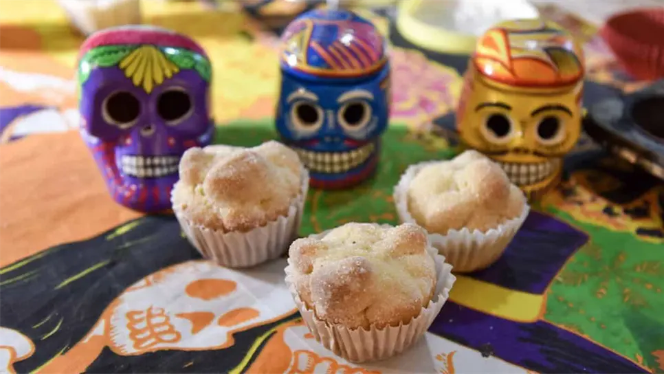 Su preparación conserva los ingredientes esenciales del pan de muerto: harina, levadura, mantequilla, huevos, ralladura de naranja y agua de azahar, pero se hornea en moldes para cupcakes, lo que facilita su presentación y distribución